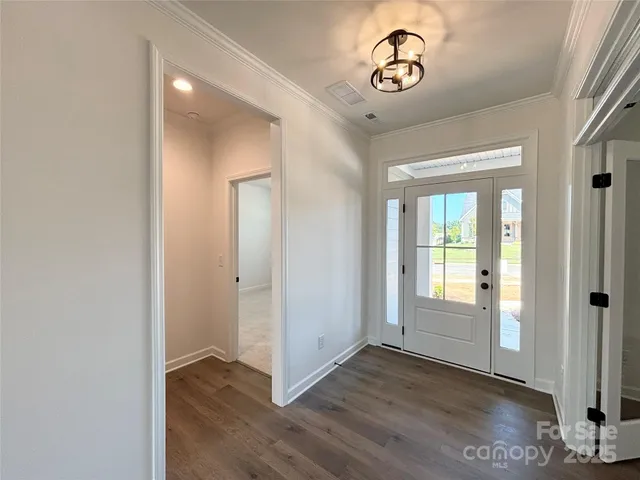 an empty room with wooden floor mirror and windows