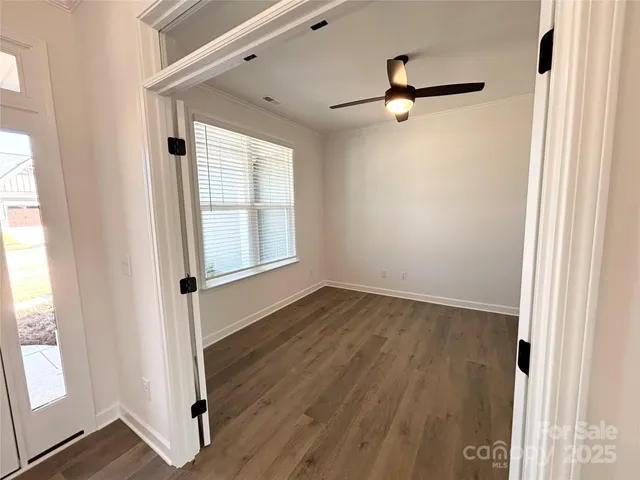 an empty room with wooden floor cabinet and windows