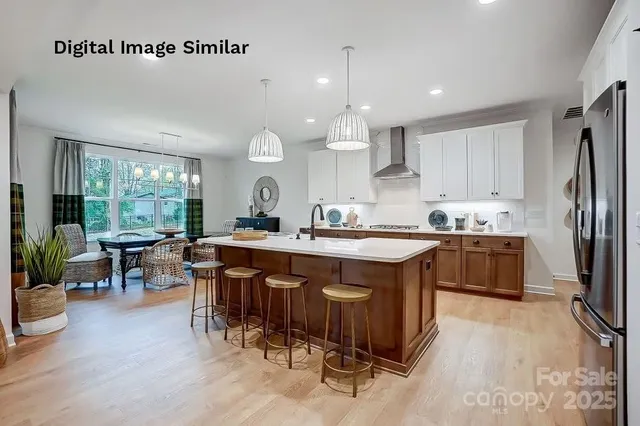 a kitchen with stainless steel appliances granite countertop a sink a stove a refrigerator and island with wooden floor