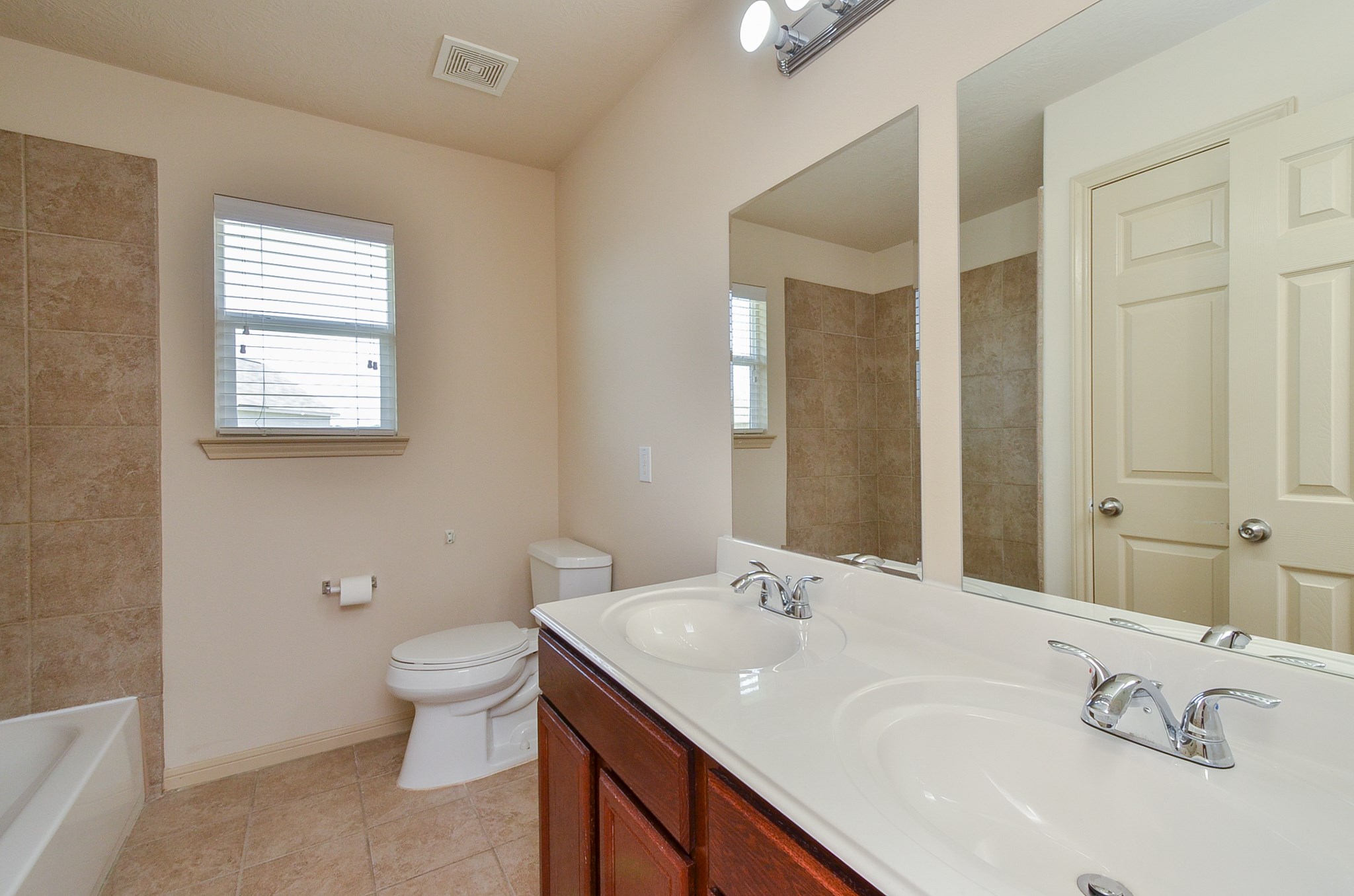 25135 Ginger Ranch Drive Katy, TX 77494 - Photo 18 of 32 Guest Bath: The primary bath features dual vanities, a large mirror, and a tub/shower combination with tile surround.