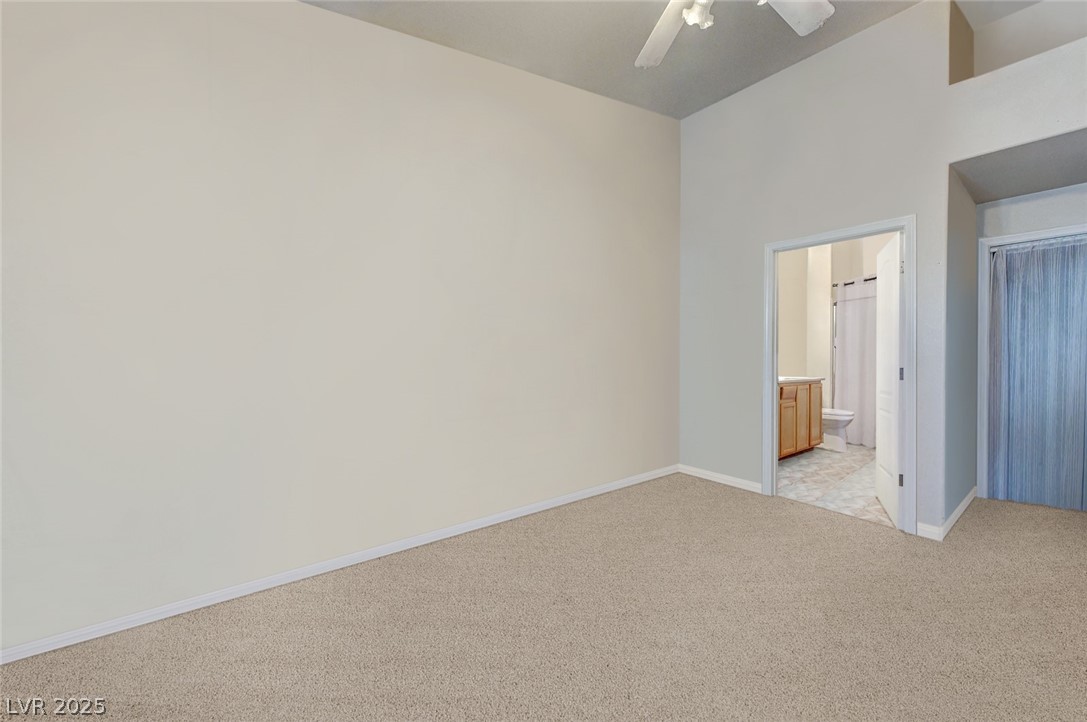 2305 West Horizon Ridge Parkway, Unit 1223 Henderson, NV 89052 - Photo 19 of 28 Unfurnished bedroom featuring light carpet, a ceiling fan, and ensuite bath