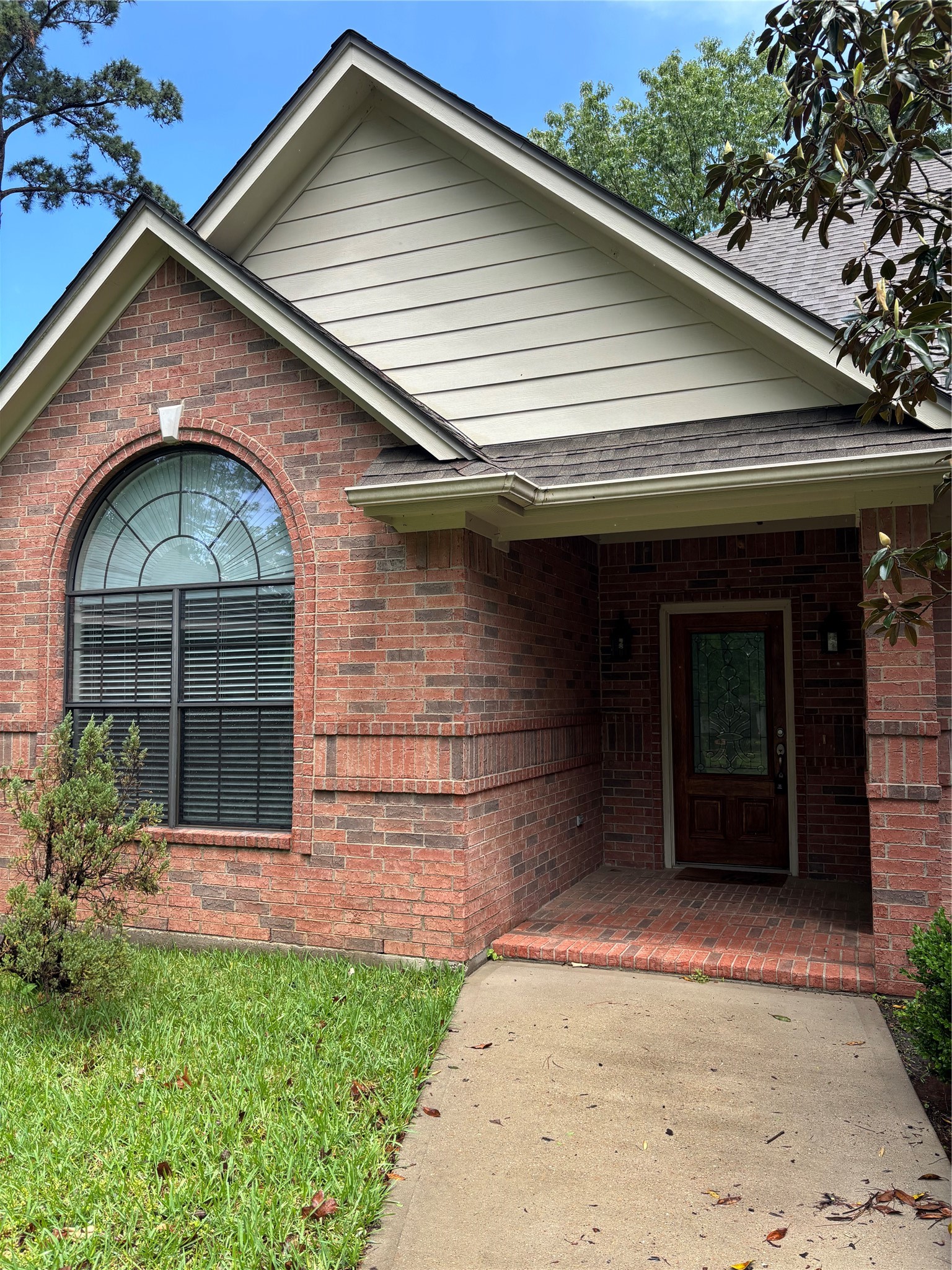 3238 Glenforest Road Montgomery, TX 77356 - Photo 2 of 41 Charming brick home with a welcoming arched window and covered front porch. The landscaped pathway leads to a wooden front door, offering a cozy and inviting entrance.
