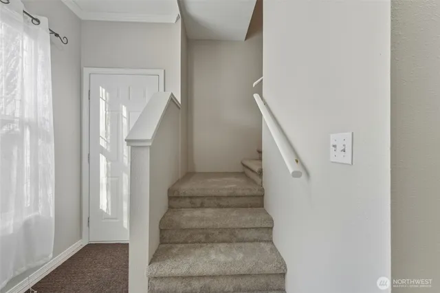 a view of staircase with white walls and white door