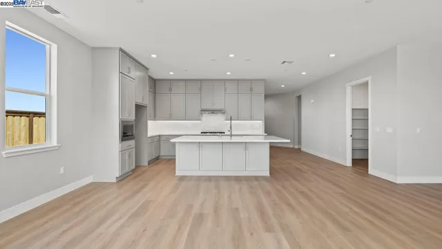 a large kitchen with a large counter top a sink stainless steel appliances and cabinets