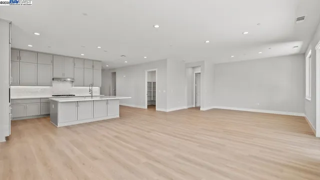 a large kitchen with stainless steel appliances granite countertop a large counter top a sink and a refrigerator