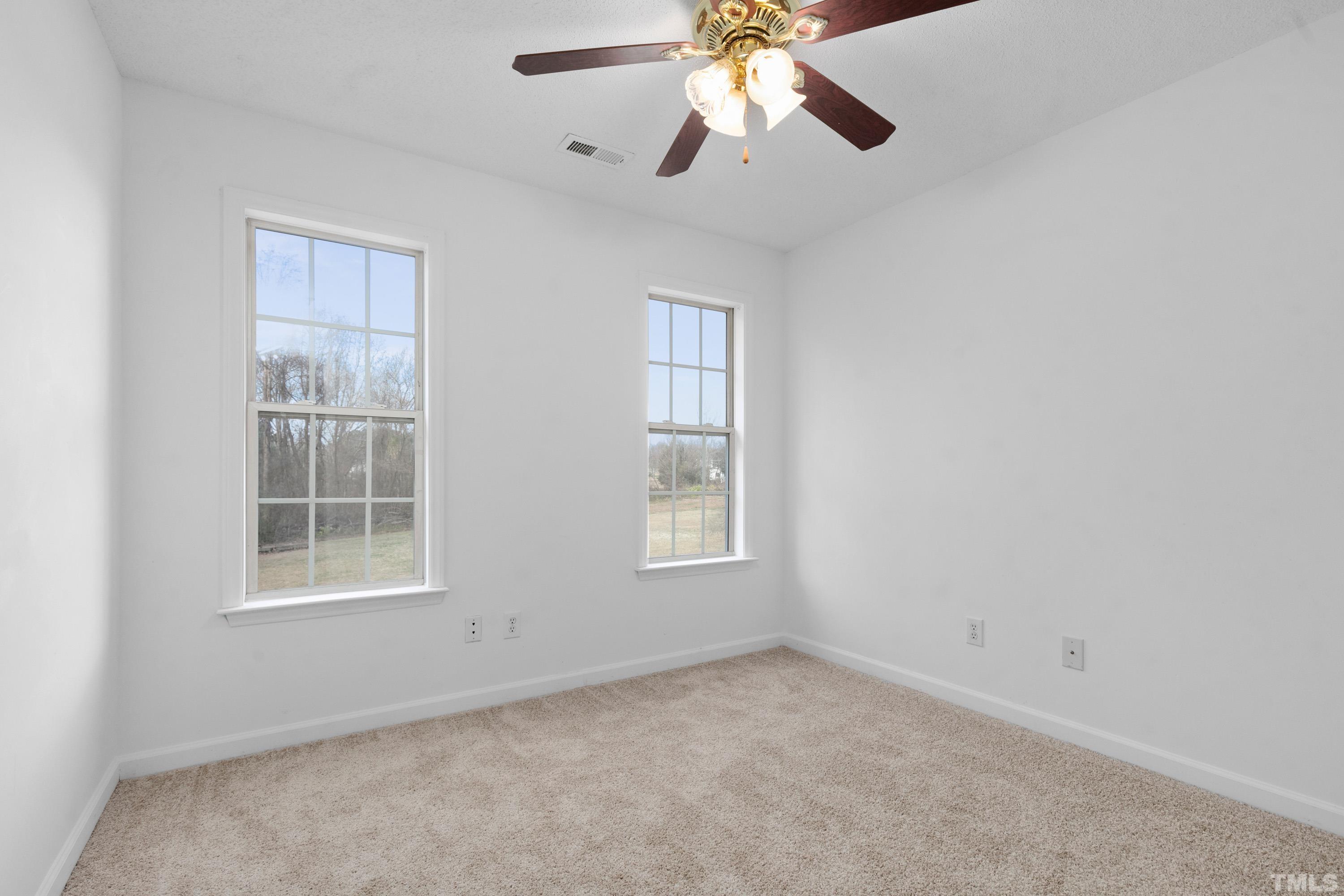 110 Saddle Ridge Drive Willow Spring, NC 27592 - Photo 23 of 32 an empty room with windows and chandelier fan