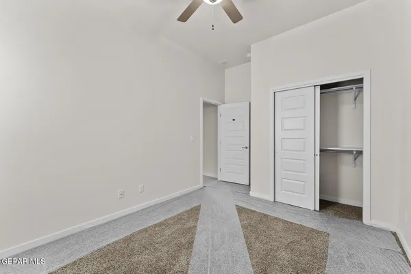 an empty room with closet and a chandelier fan