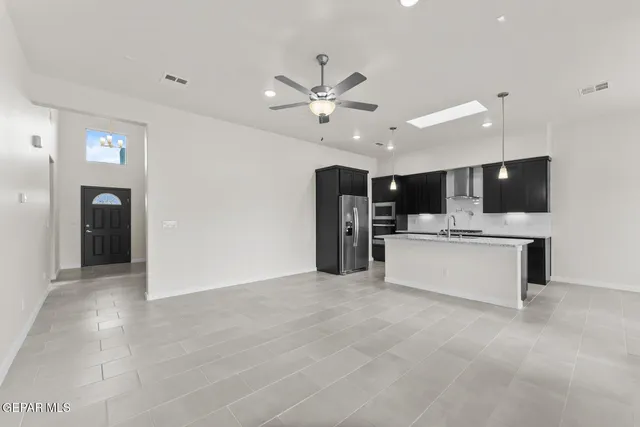 a view of an empty room with kitchen appliances and a ceiling fan
