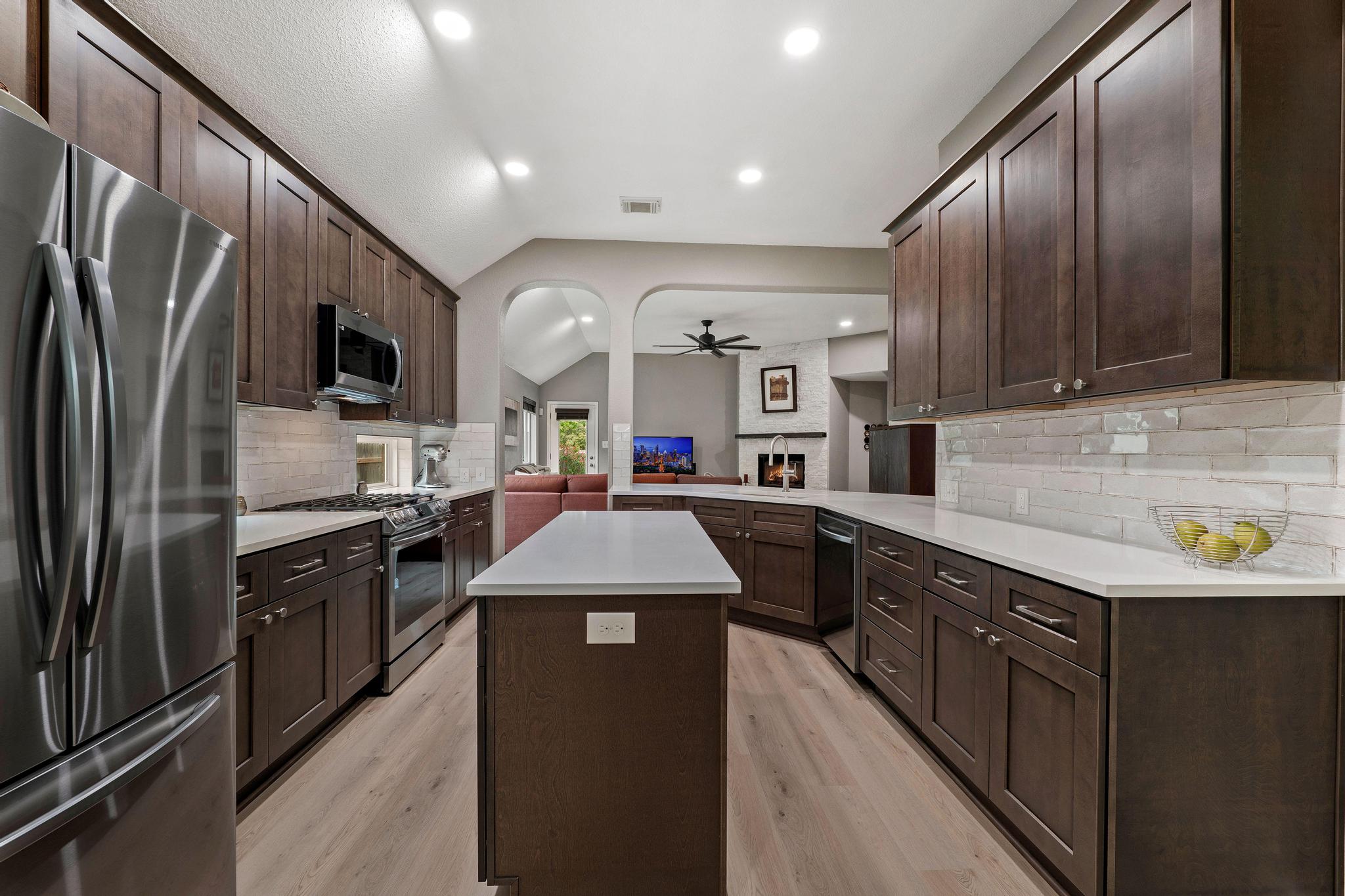 13231 Armaga Springs Road Austin, TX 78727 - Photo 36 of 36 Kitchen with stainless steel appliances, vaulted ceiling, a peninsula, dark wood finish cabinetry, and open floor plan