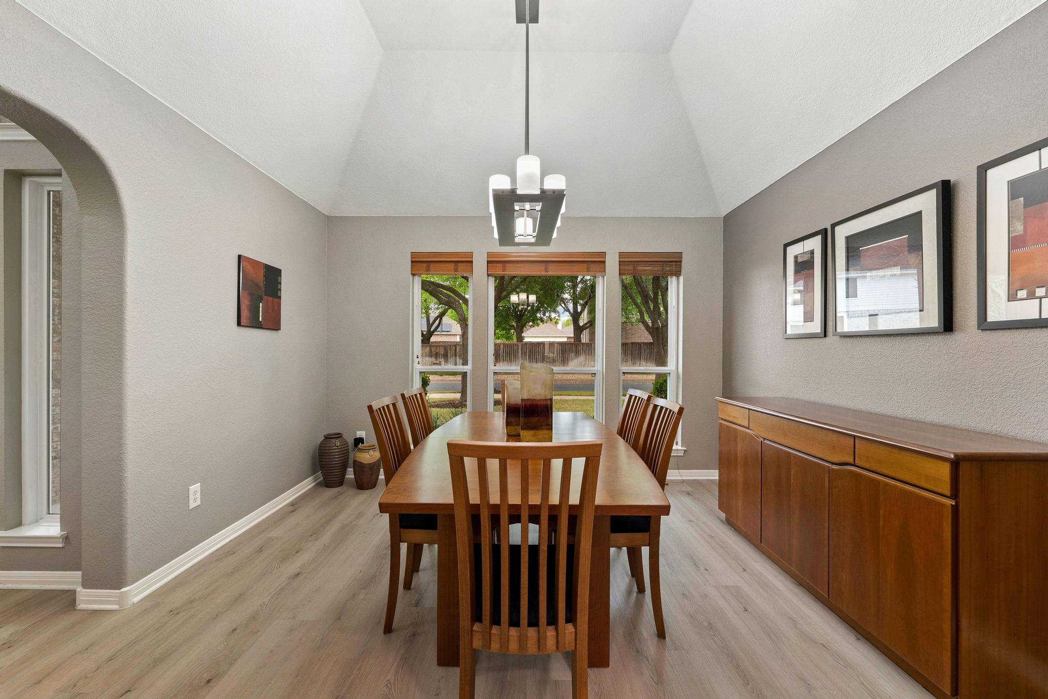 13231 Armaga Springs Road Austin, TX 78727 - Photo 13 of 36 Dining room featuring arched walkways, light wood-style floors, vaulted ceiling, and hanging lights