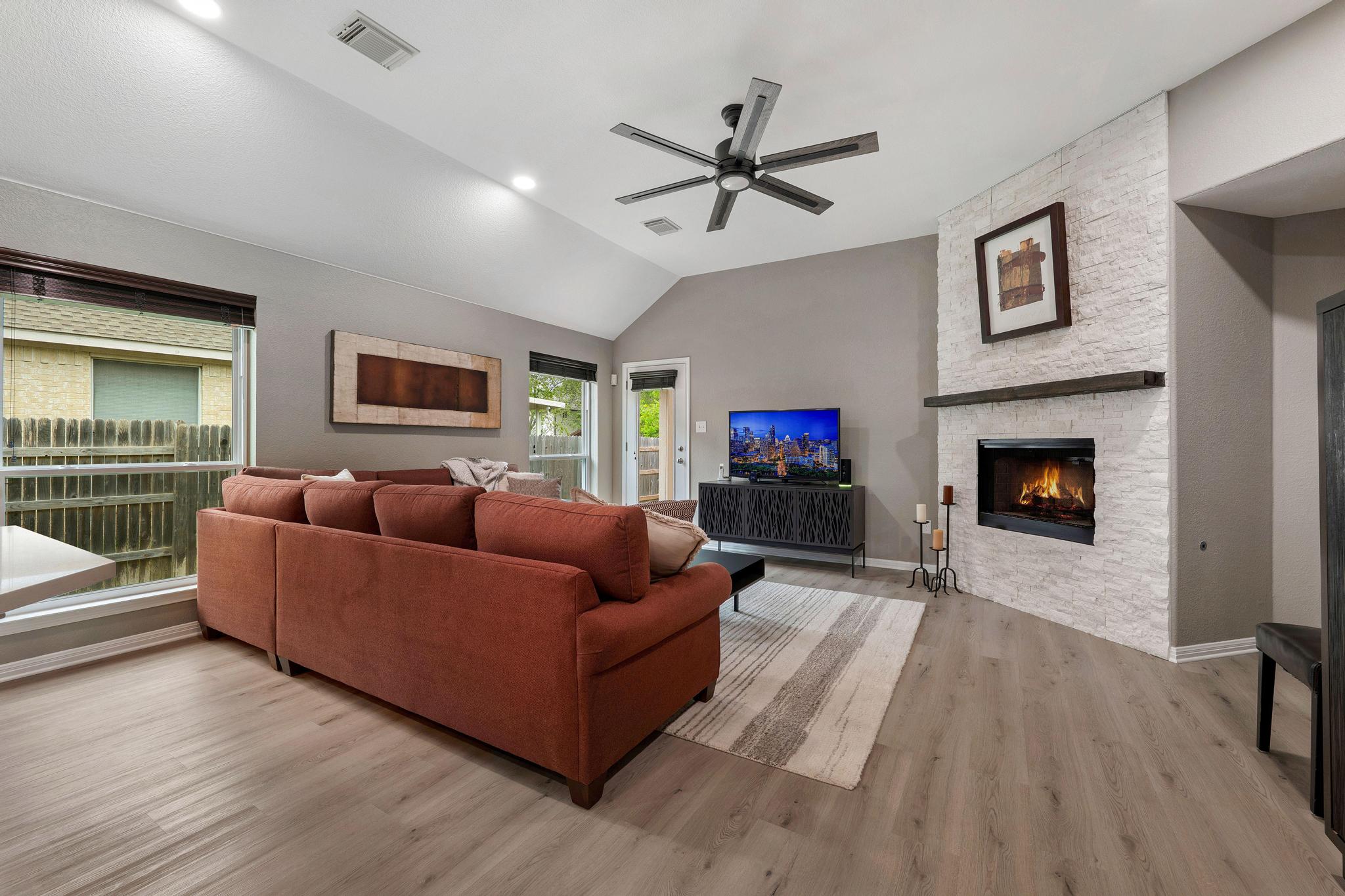 13231 Armaga Springs Road Austin, TX 78727 - Photo 15 of 36 Living room featuring a fireplace, light wood-style floors, ceiling fan, and lofted ceiling