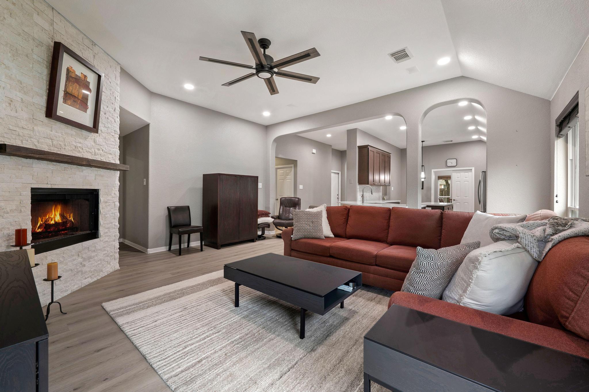 13231 Armaga Springs Road Austin, TX 78727 - Photo 19 of 36 Living area with a fireplace, a ceiling fan, light wood finished floors, lofted ceiling, and arched walkways
