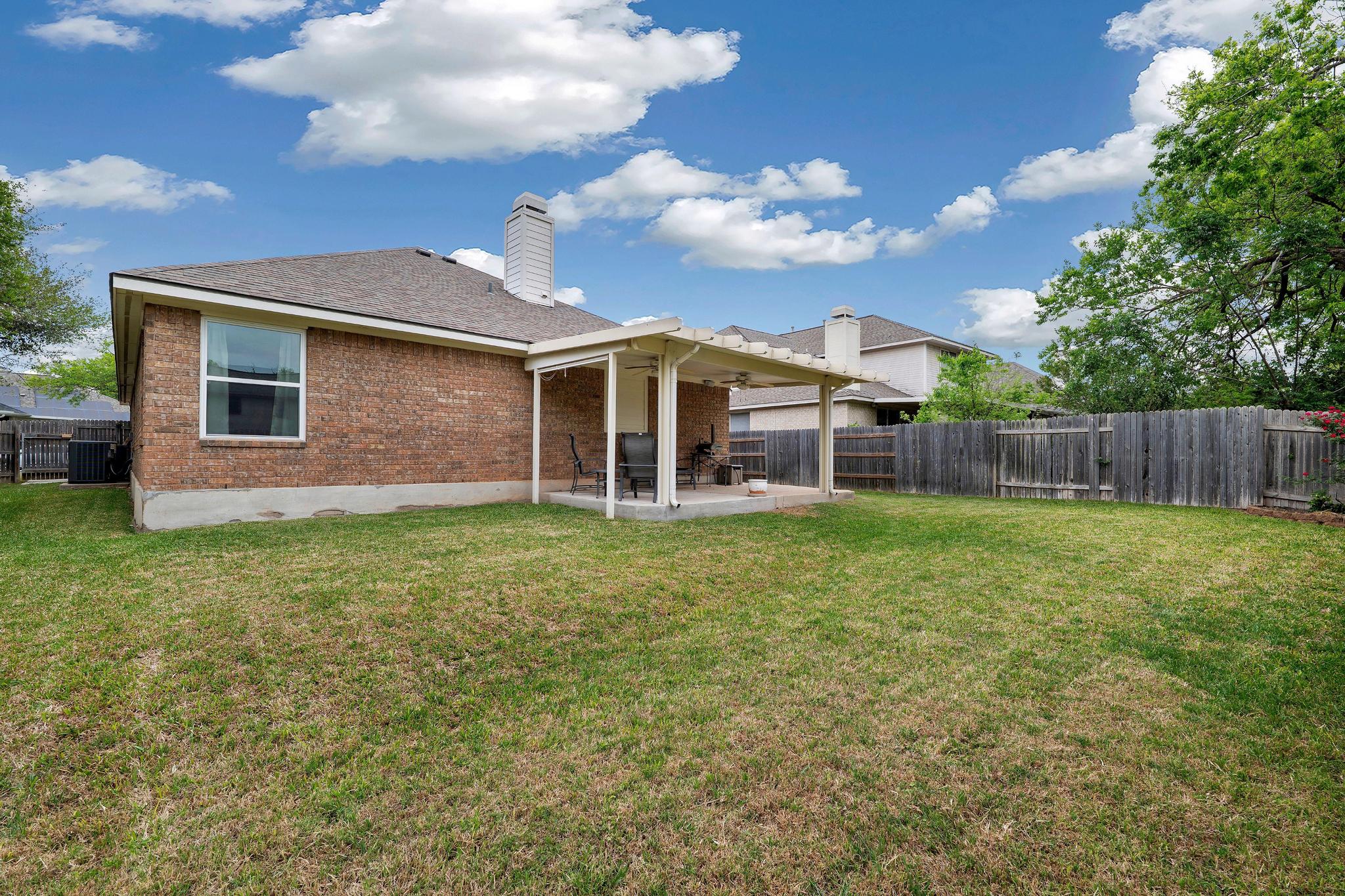 13231 Armaga Springs Road Austin, TX 78727 - Photo 31 of 36 Back of property featuring a patio area, brick siding, a fenced backyard, a chimney, and roof with shingles