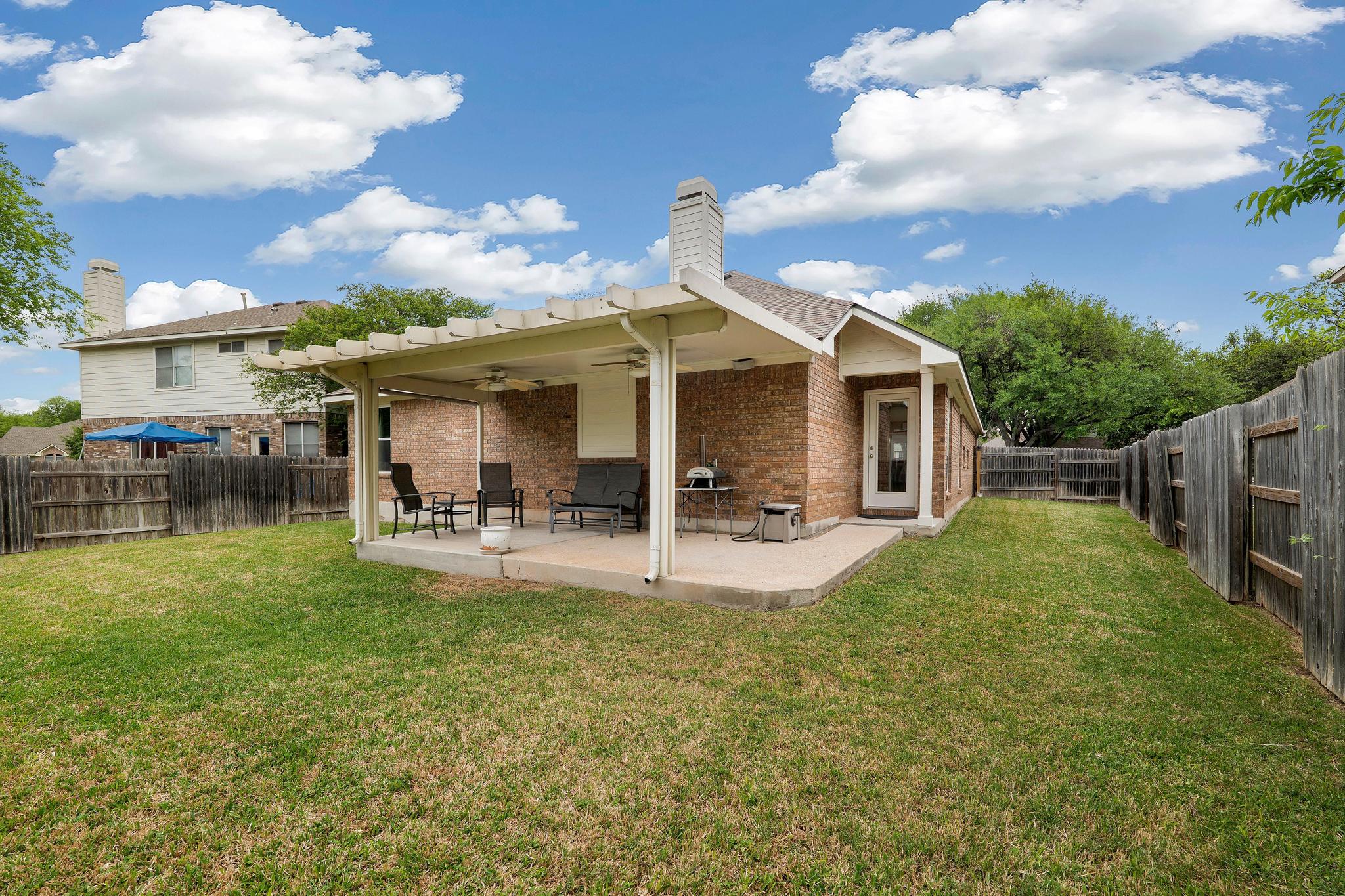 13231 Armaga Springs Road Austin, TX 78727 - Photo 32 of 36 Rear view of house featuring ceiling fan, a patio area, brick siding, and a fenced backyard