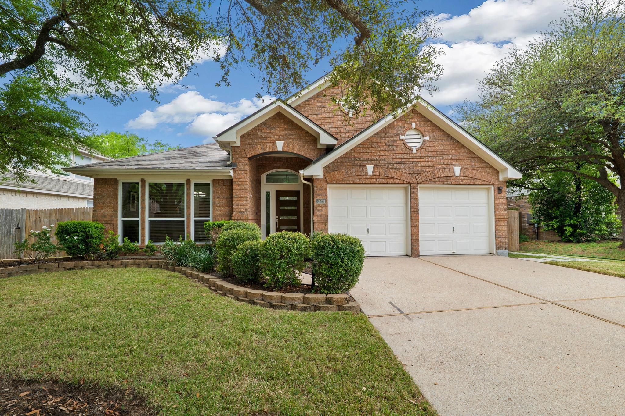 13231 Armaga Springs Road Austin, TX 78727 - Photo 5 of 36 View of front facade with brick siding, driveway, and a garage