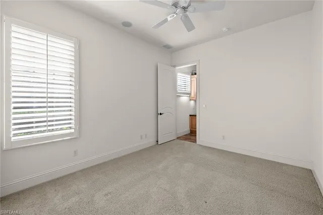 an empty room with a window and a fan