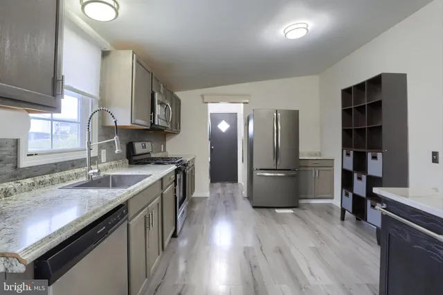 a kitchen with stainless steel appliances granite countertop a refrigerator a stove and a sink