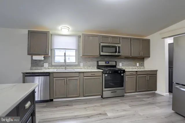 a kitchen with stainless steel appliances granite countertop a stove top oven a sink dishwasher and microwave