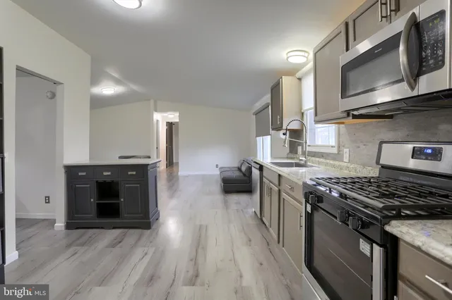 a kitchen with stainless steel appliances granite countertop a stove a sink and a microwave