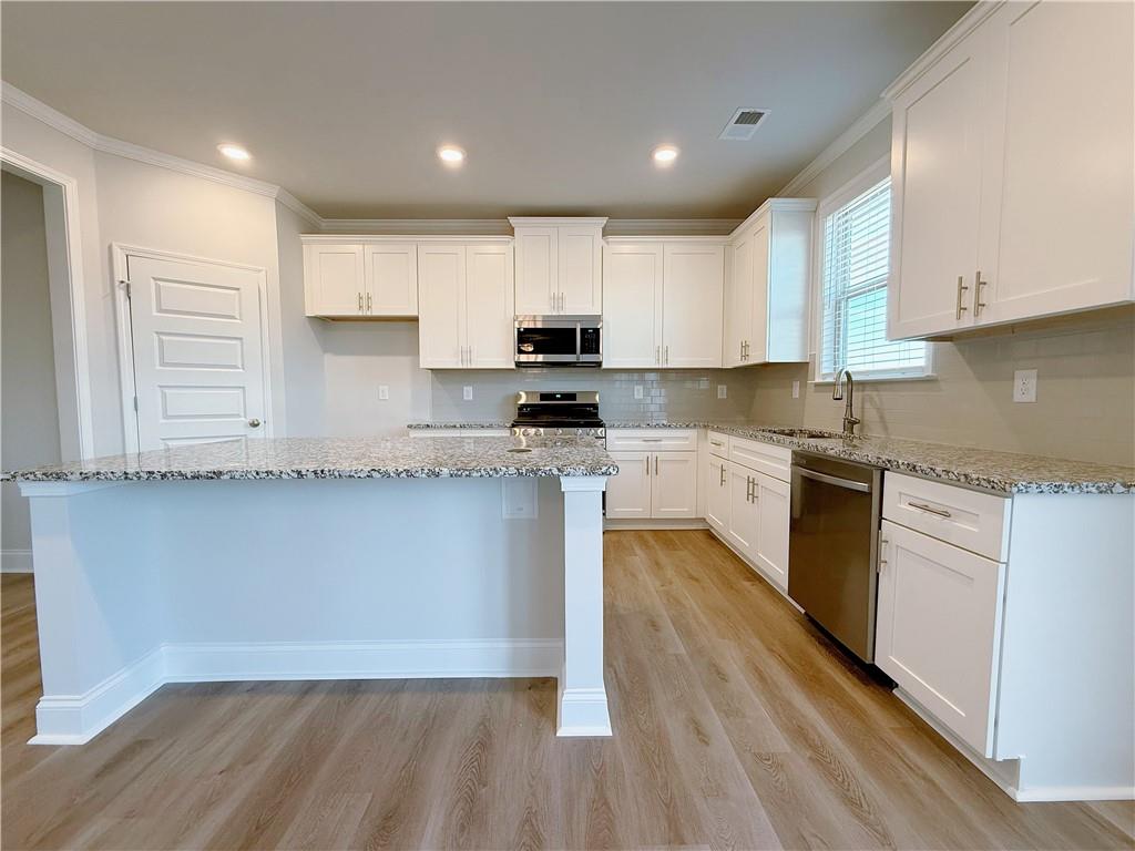 1450 Sunny Valley Lane Braselton, GA 30517 - Photo 8 of 24 a kitchen with granite countertop a stove a sink and white cabinets
