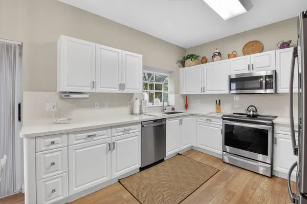 a kitchen with cabinets stainless steel appliances and wooden floor