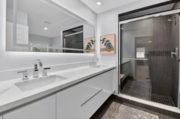 a bathroom with a double vanity sink mirror and shower
