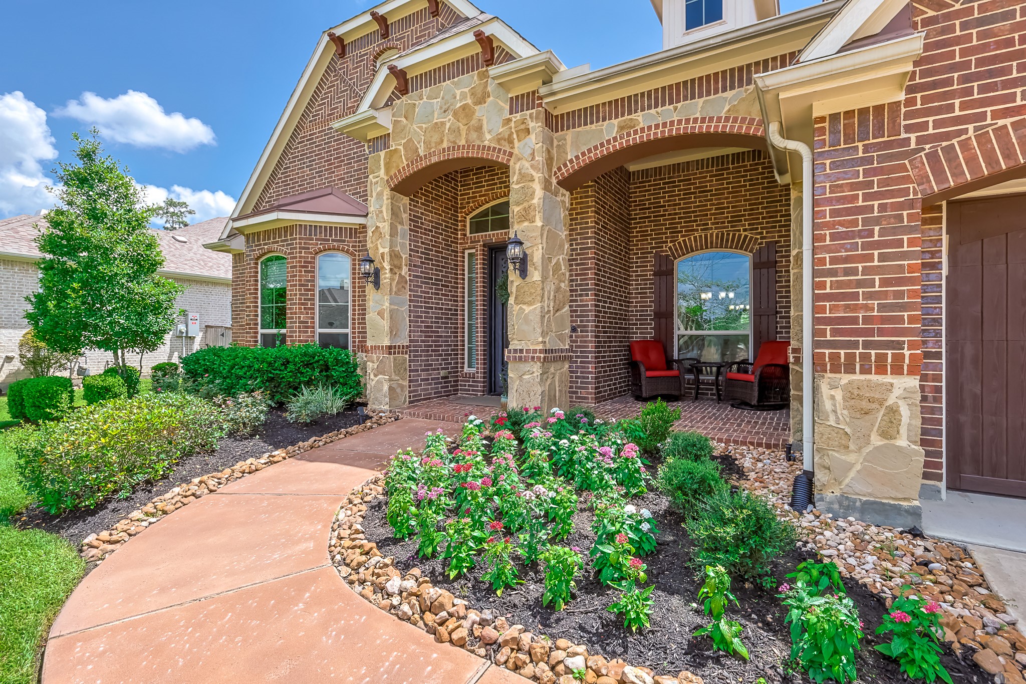 515 Mill Creek Road Pinehurst, TX 77362 - Photo 2 of 48 Enjoy time with the neighbors on the welcoming front porch. The lush landscaping features vibrant flowers and manicured shrubs, leading to a cozy seating area.