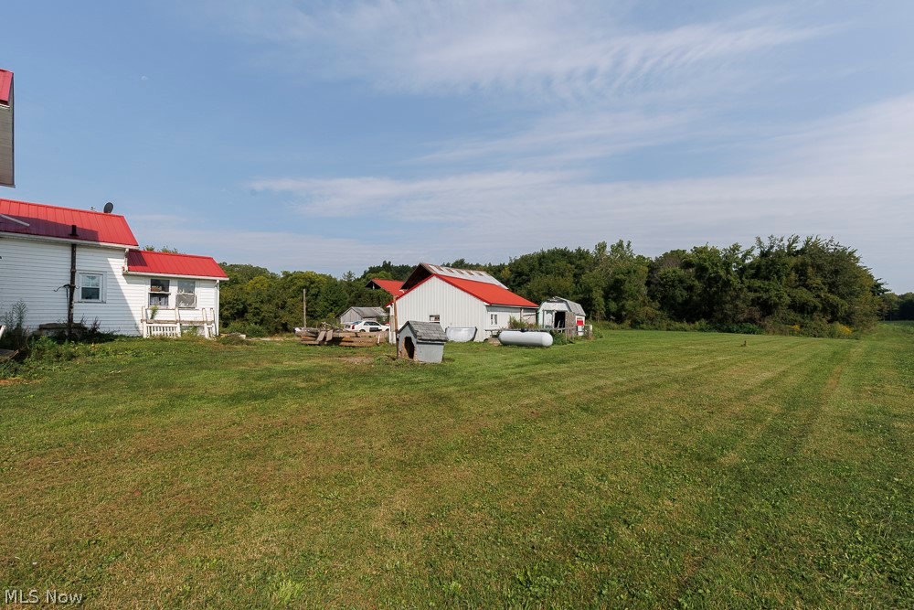 5366 Zenobia Road Wakeman, OH 44889 - Photo 24 of 25 Expansive grassy yard with multiple white-sided structures featuring red roofs, surrounded by mature trees