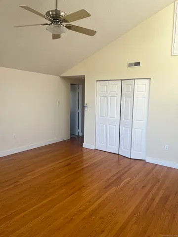an empty room with wooden floor fan and windows