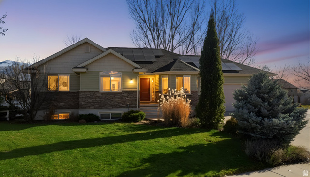 2882 South 1080th Street West Logan, UT 84321 - Photo 1 of 1 View of front of property with a lawn, solar panels, an attached garage, and stone siding