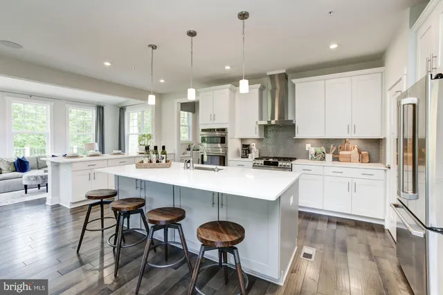 a kitchen with stainless steel appliances granite countertop white cabinets a sink a stove a dining table and chairs