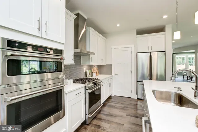 a kitchen with cabinets stainless steel appliances and wooden floor