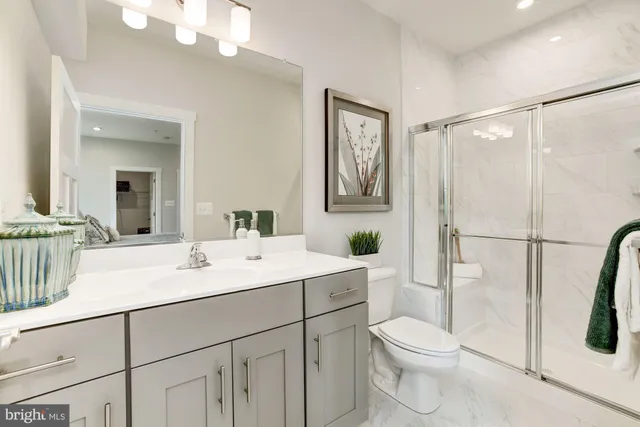 a bathroom with a sink a toilet a mirror and shower