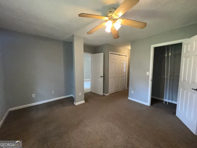 an empty room with closet and a chandelier fan