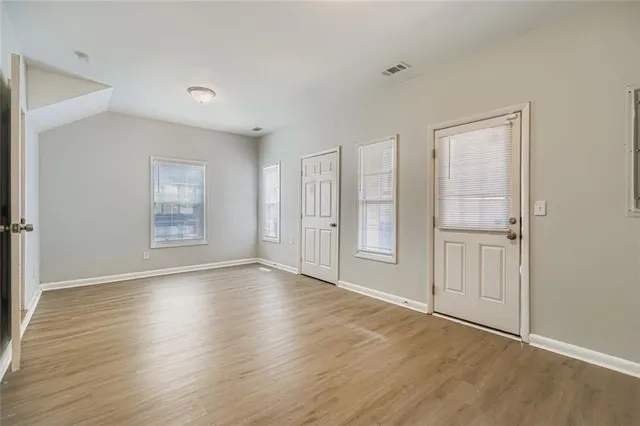 a view of an empty room with wooden floor and a window
