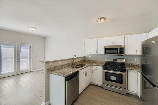 a kitchen with stainless steel appliances granite countertop a stove a sink and a microwave