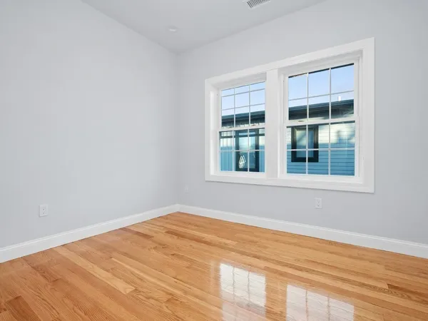 a view of empty room with wooden floor and windows