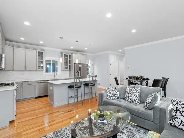 a living room with furniture kitchen view and a wooden floor