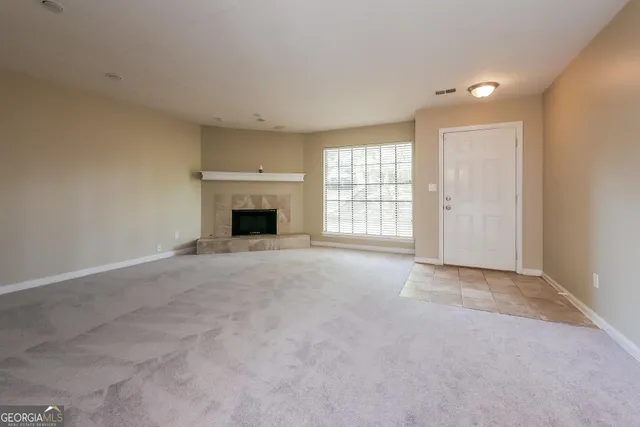 a view of an empty room with a fireplace and a window
