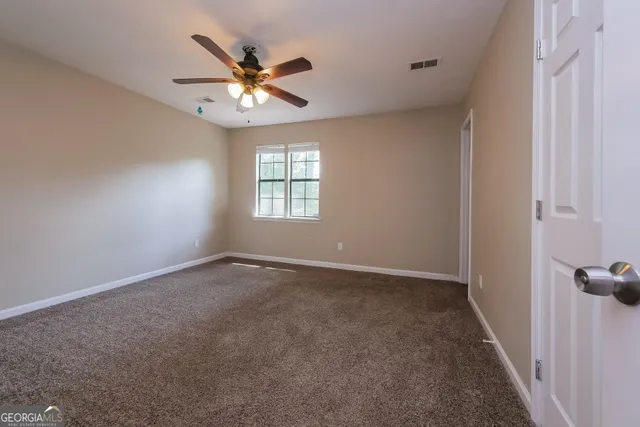a view of an empty room with a chandelier fan