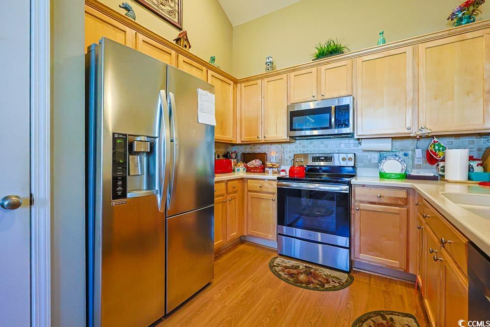 75 Field Planters Circle, Unit 75 Calabash, NC 28467 - Photo 7 of 40 Kitchen with appliances with stainless steel finishes, light countertops, light wood finished floors, tasteful backsplash, and light brown cabinets