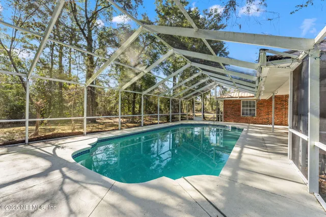 a view of a swimming pool with a patio and a yard