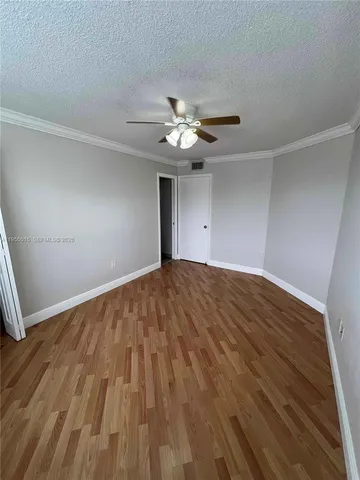 a view of empty room with wooden floor and fan