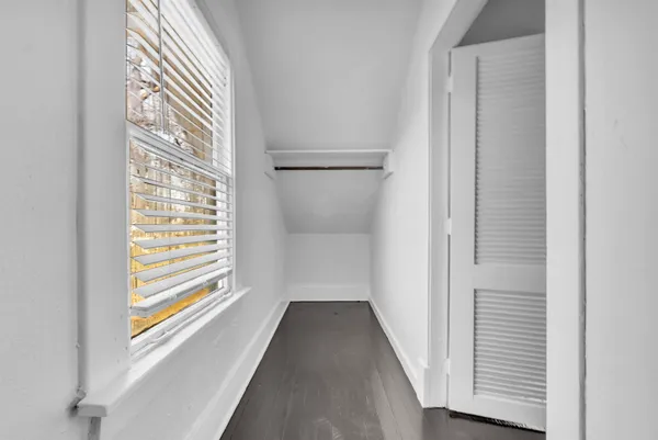 a view of a hallway with wooden floor and a bathroom