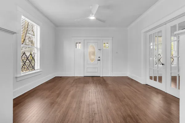 an empty room with wooden floor and windows
