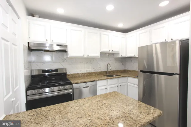 a kitchen with granite countertop a refrigerator stove top oven and sink