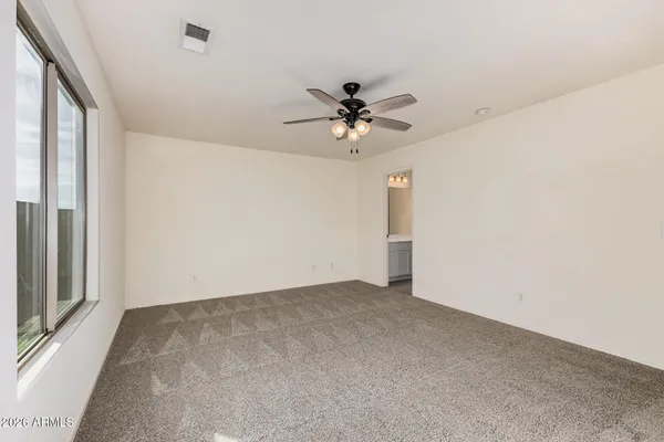 an empty room with a chandelier fan and windows