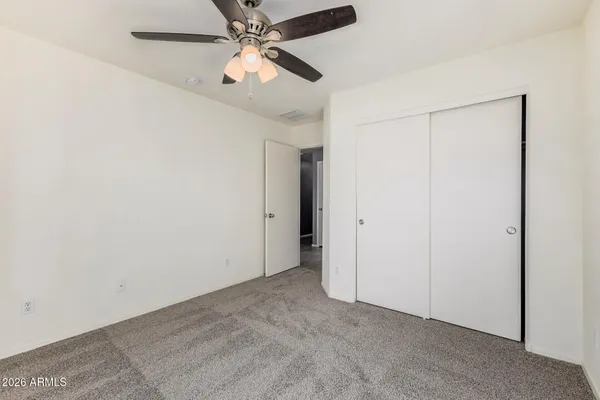 an empty room with closet and a chandelier fan