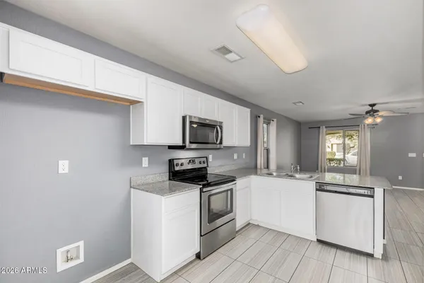 a kitchen with stainless steel appliances a white stove top oven a sink dishwasher and a refrigerator with wooden floor