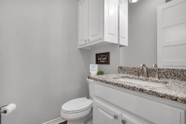 a bathroom with a granite countertop toilet sink and mirror